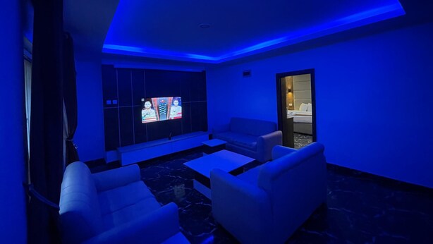 A modern living room with a flat-screen TV, white sofas, and a marble floor. - PRESKEN HOTELS FAJODD4 (Lagos)