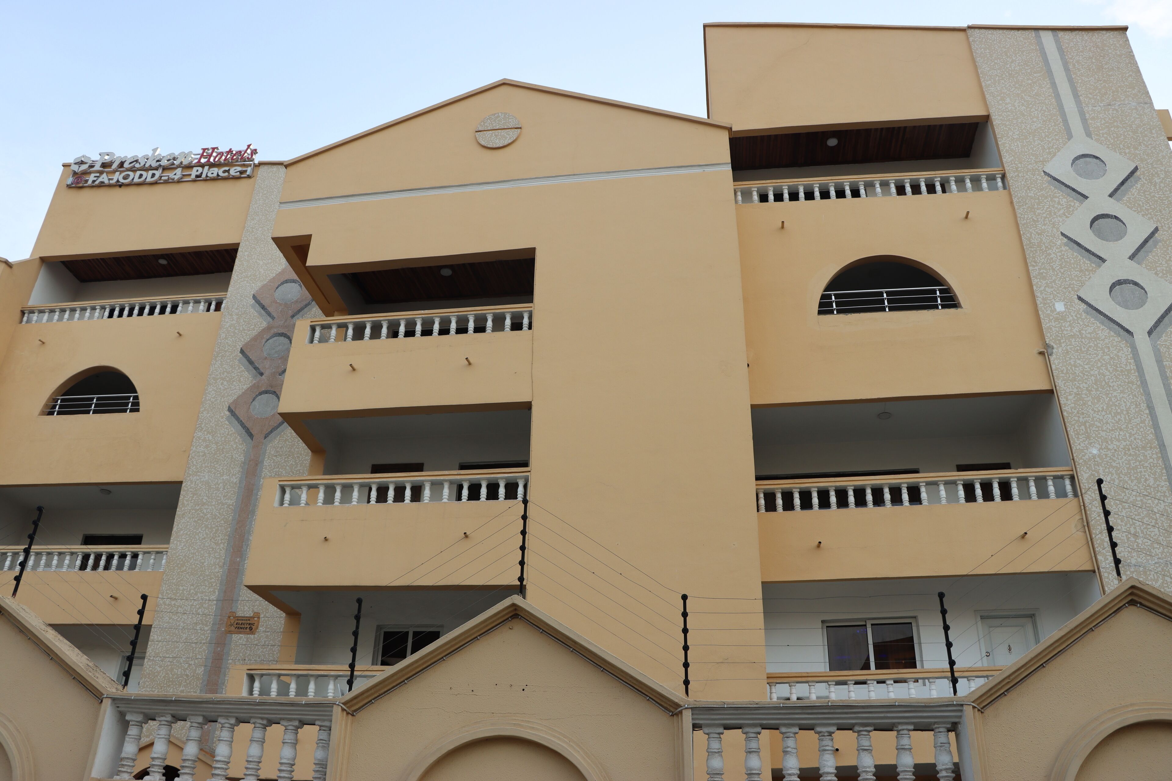 A multi-story hotel with balconies, a central stairway, and a sign indicating it is a hotel.