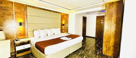 Habitación de hotel con cama, mesita de noche, lámpara y un revestimiento de pared de madera.