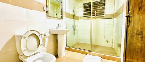 Un bagno con WC, lavandino e box doccia in vetro.