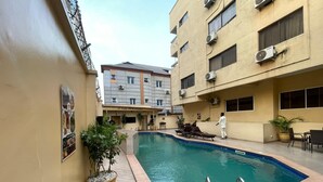 A swimming pool area with a tiled deck, lounge chairs, and a potted plant. - PRESKEN HOTELS FAJODD4 (Lagos)