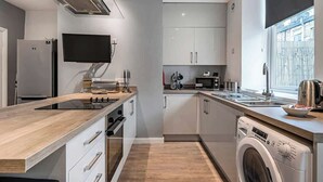 Una cocina moderna con horno empotrado, microondas y lavavajillas, un ventanal grande y un televisor de pantalla plana montado sobre la encimera.