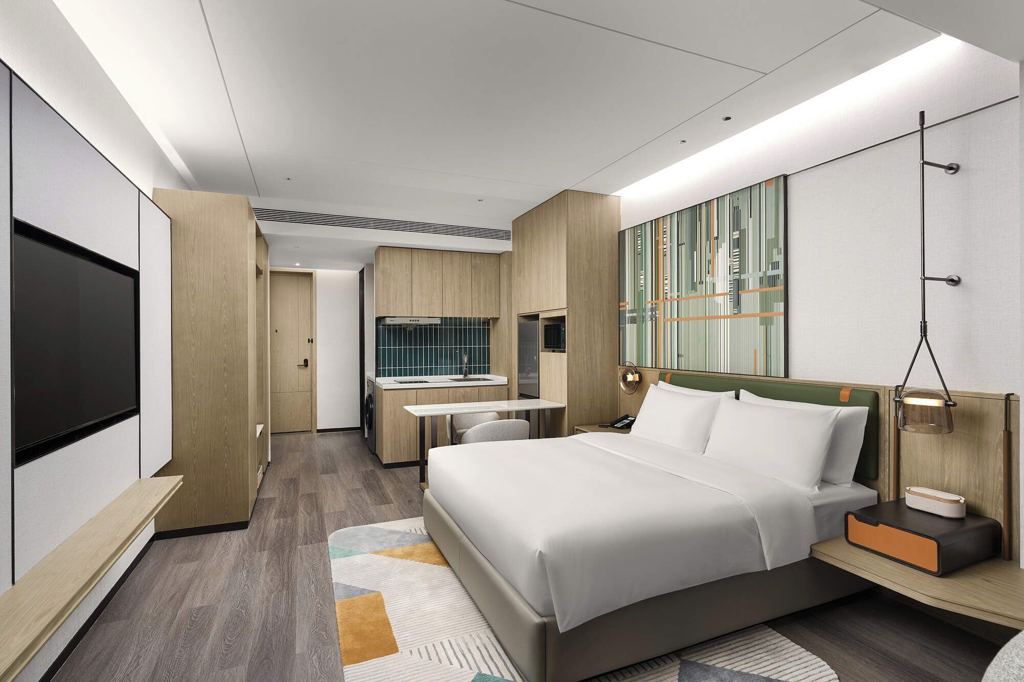 A modern hotel room with a large bed, a desk, a mirror, and a TV.