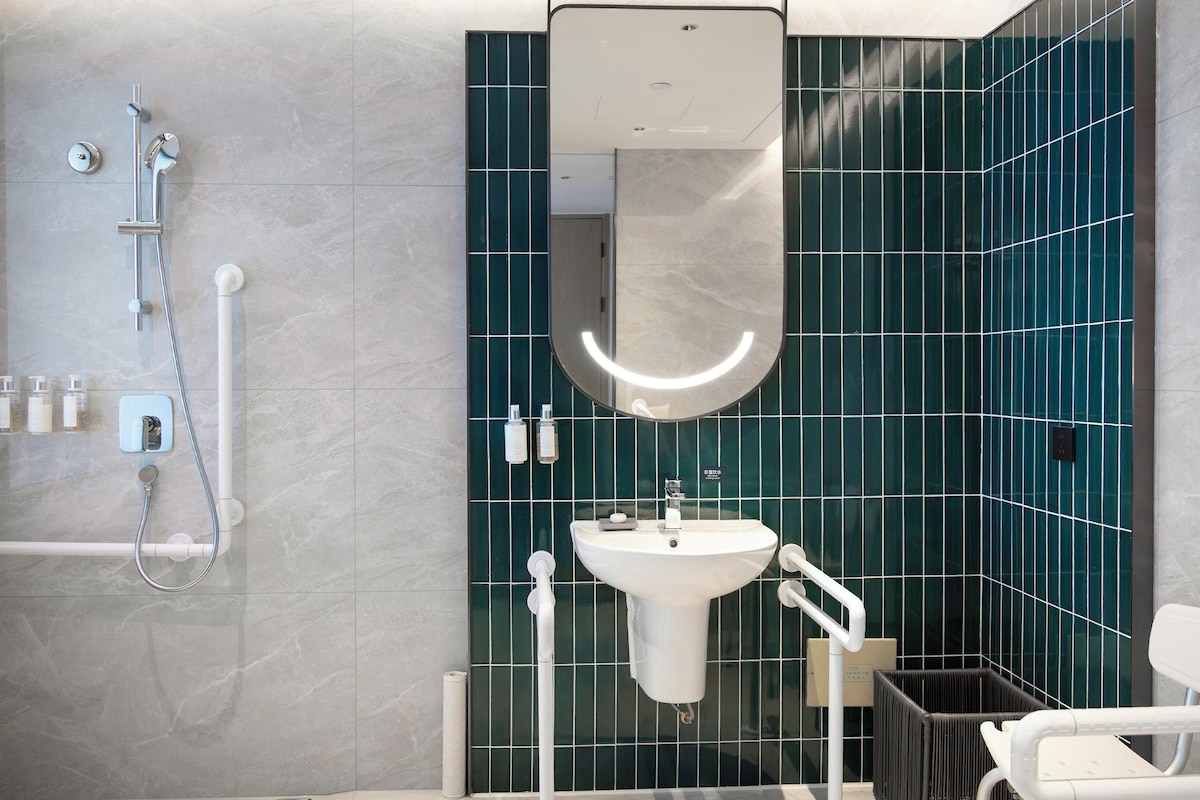 A modern bathroom with a white sink, a mirror, and a shower area.