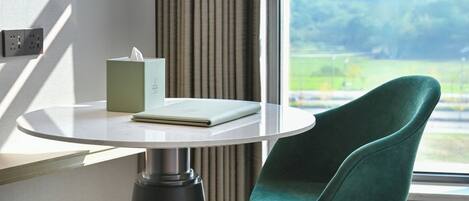 A room with a round table, a green chair, a tissue box, and a notebook.