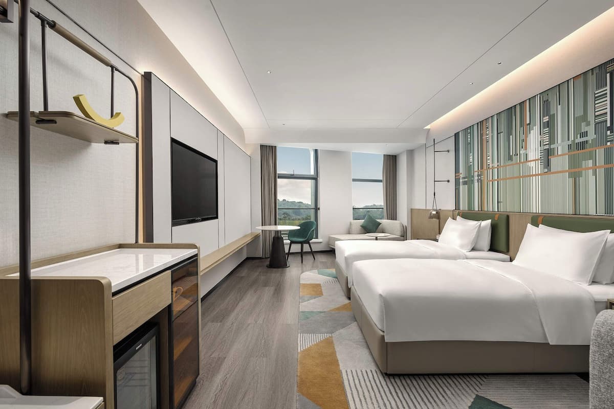 Una camera d'hotel moderna con un letto grande, una scrivania, una TV e vista sull'esterno.