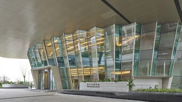 Een modern congrescentrum met een glazen gevel en een grote uitbouw.