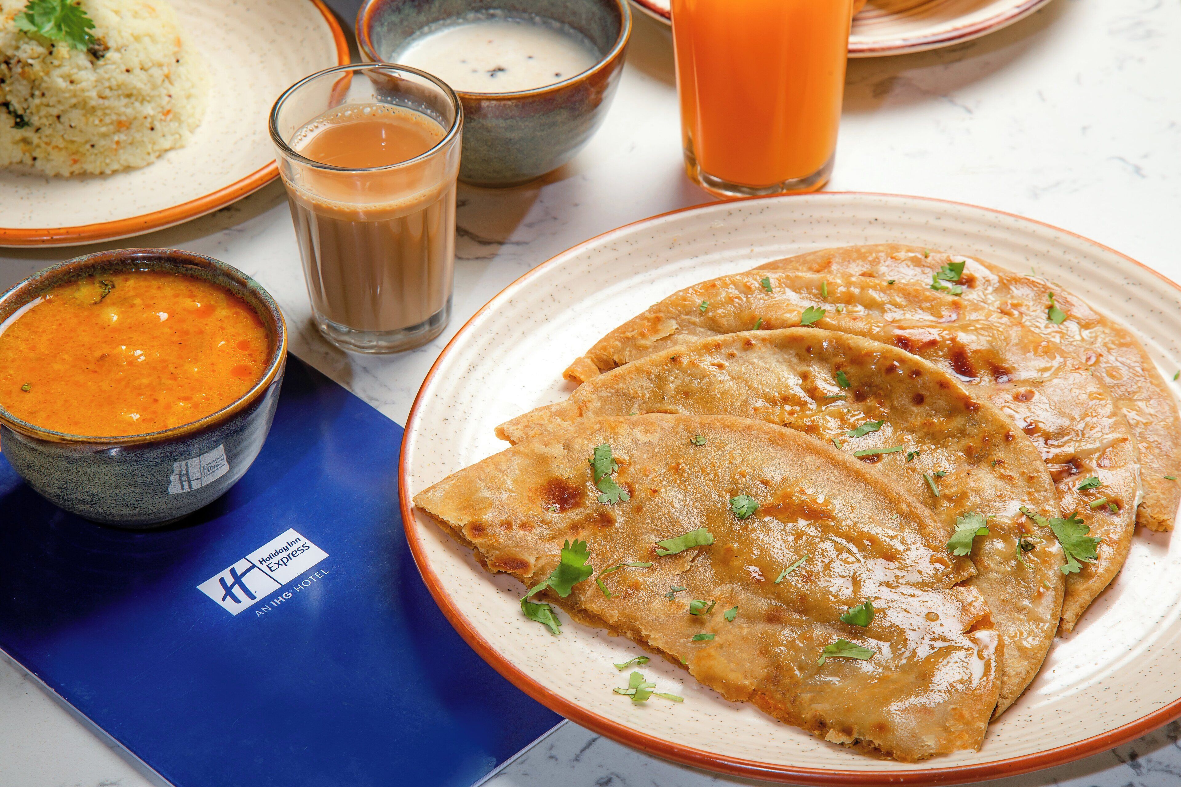 A plate of food with a bowl of soup and a glass of orange juice on a table.