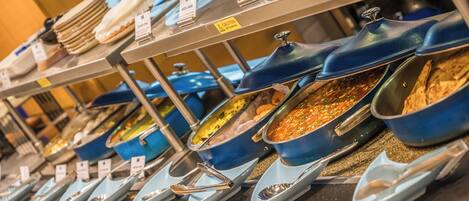 A buffet with various dishes in blue and white bowls, each labeled with the dish name.