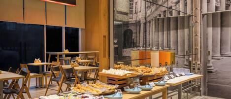 A buffet area with various food items and a large window with a cityscape view.