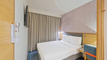 Una habitación de hotel con cama, escritorio, silla, televisor y cafetera.