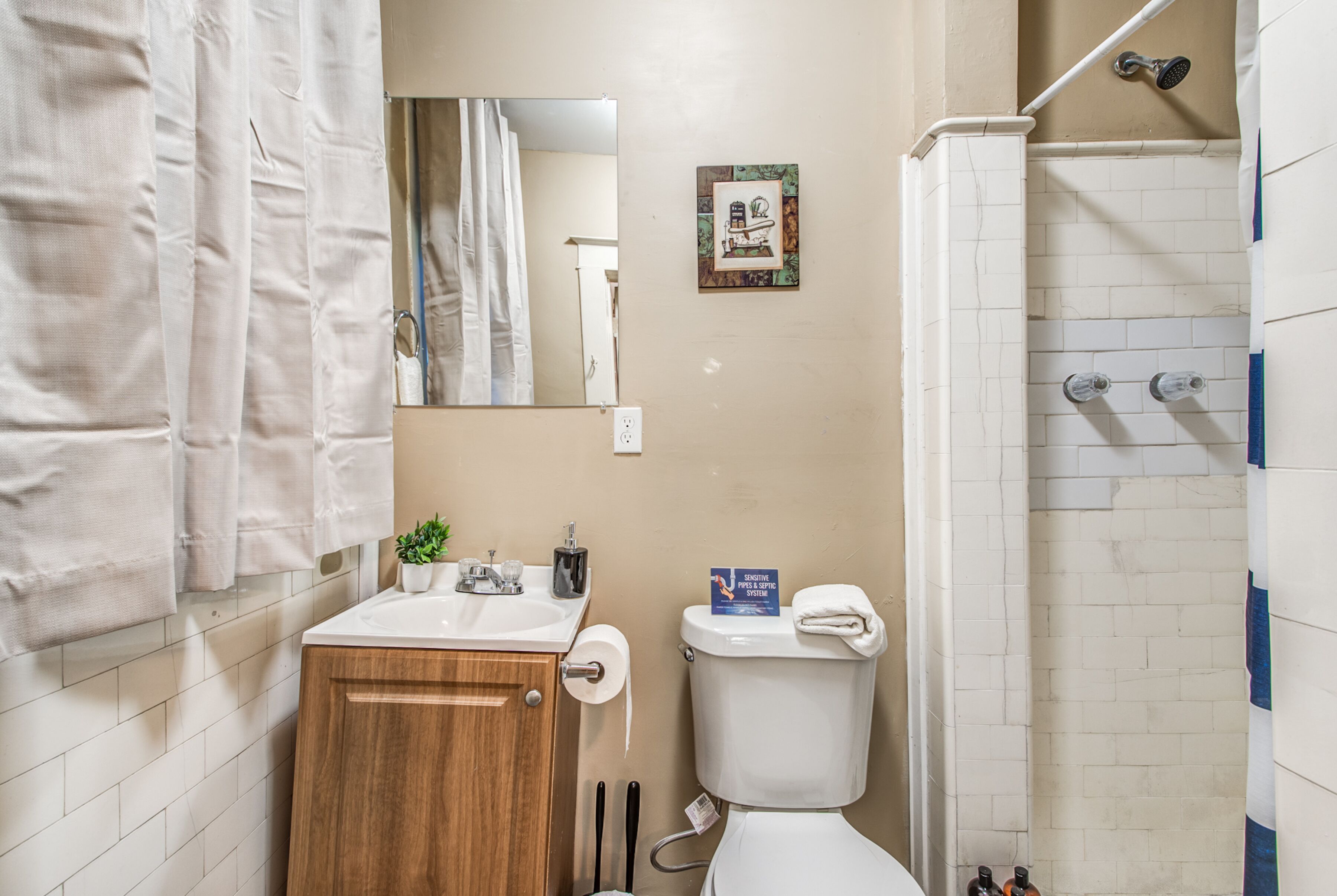 A bathroom with a wooden cabinet, a toilet, a sink, and a shower.