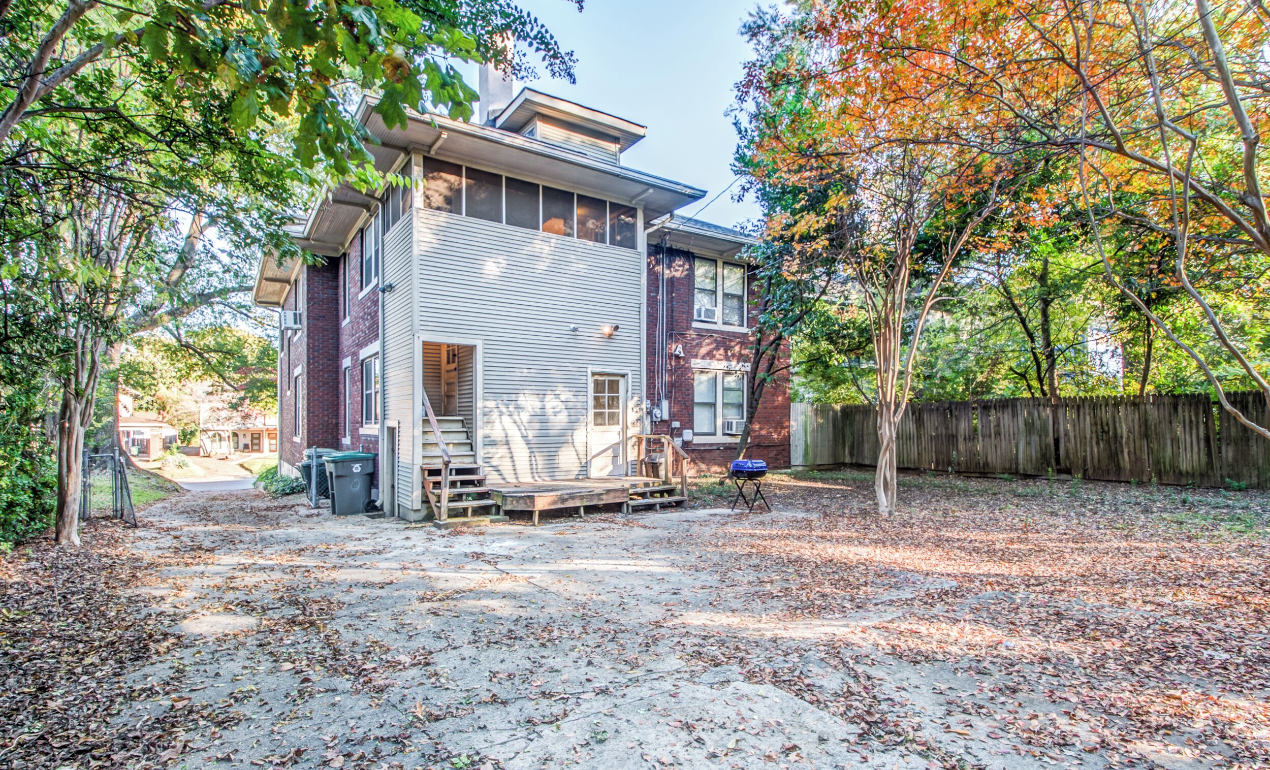 A two-story house with a covered porch and a fenced yard.