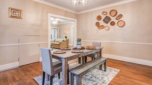 A dining room with a wooden table, benches, and a chandelier. - Bluemoon Bungalow 2 Units (Memphis)