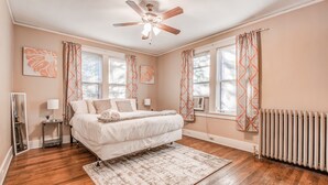 A bedroom with a large bed, a ceiling fan, and a radiator. - Bluemoon Bungalow 2 Units (Memphis)