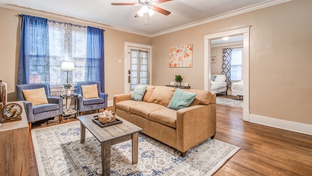 A living room with a beige sofa, two armchairs, a coffee table, and a ceiling fan. - Bluemoon Bungalow 2 Units (Memphis)