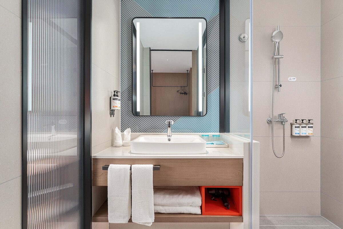 A modern bathroom with a glass shower enclosure, a white sink, and a mirror above it.