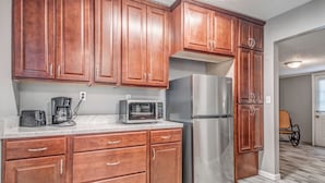 A kitchen with wooden cabinets, a stainless steel refrigerator, a microwave, and a coffee maker. - Shelby Parks Farm Haddington Home (Memphis)