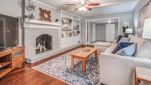 A living room with a fireplace, wooden coffee table, and a sofa with cushions. - Shelby Parks Farm Haddington Home (Memphis)