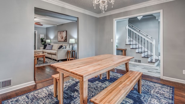 A spacious living room with a wooden dining table, benches, and a chandelier. - Shelby Parks Farm Haddington Home (Memphis)