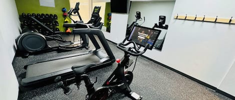Un gimnasio con equipos de ejercicio variados, incluyendo cintas de correr, bicicletas estáticas y pesas.