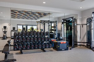 A gym with various exercise equipment, including dumbbells, a squat rack, and a bench.