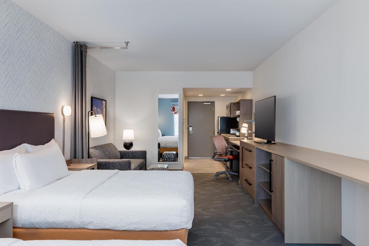 Een hotelkamer met een bed, bureau, stoel, lamp en televisie.