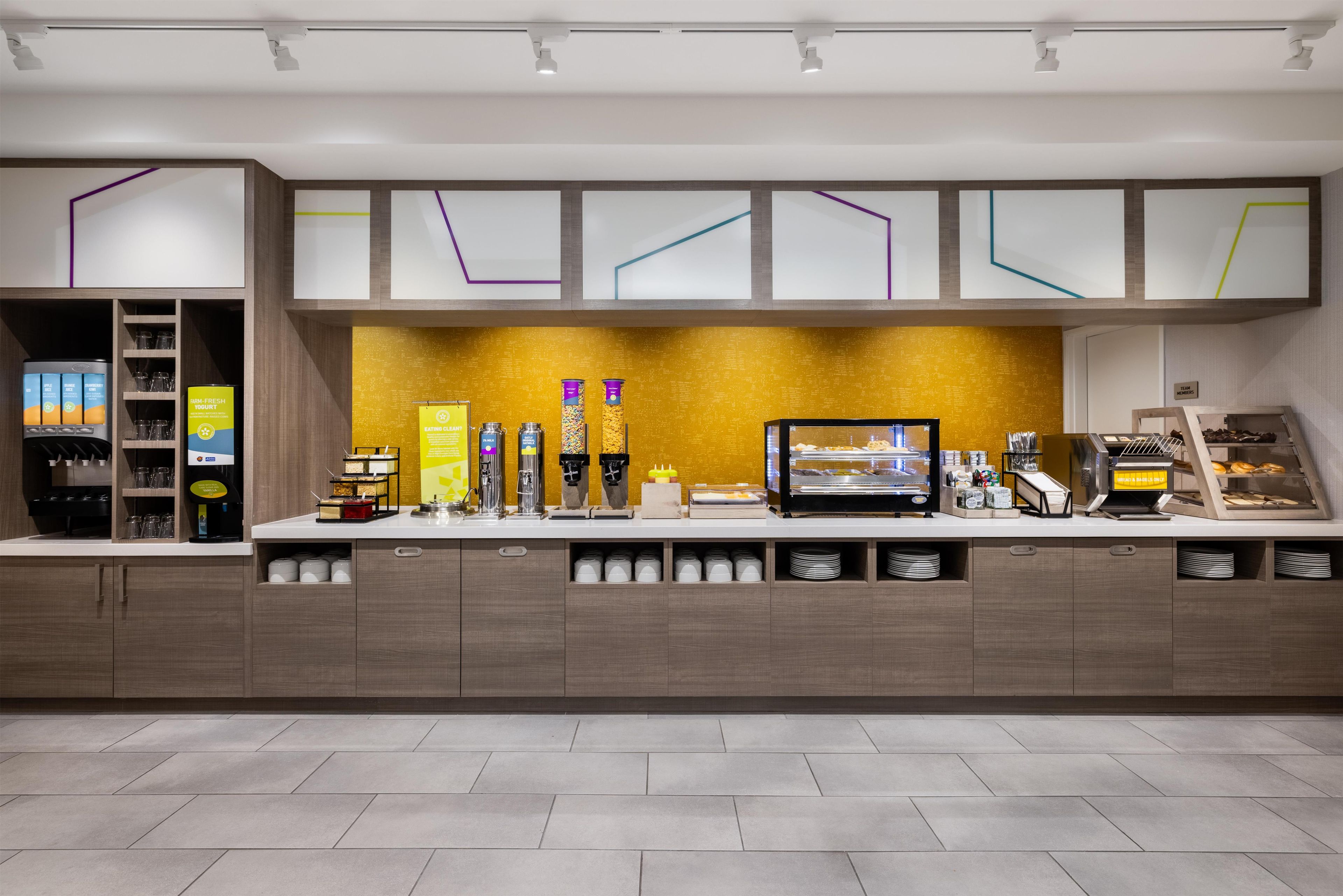 A modern breakfast bar with a variety of food and drink options, including a coffee machine and a selection of yogurts.