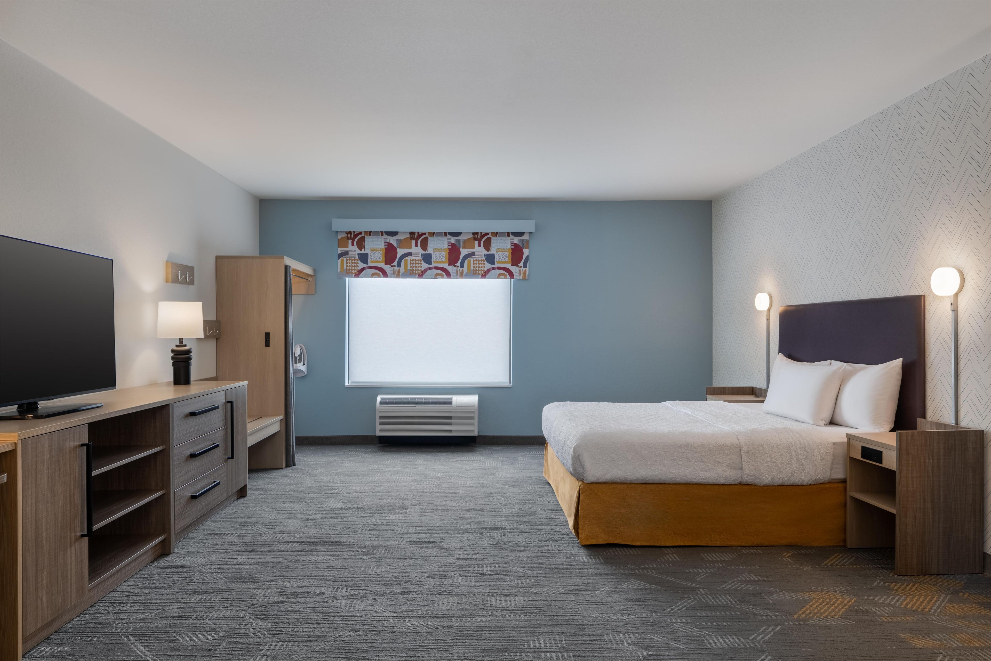 Una habitación de hotel con cama, televisión, escritorio y ventana.