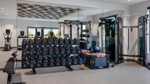 Ein modernes Fitnessstudio mit Gewichtstrainingsgeräten, einer Trainingsbank und einer Spiegelwand.