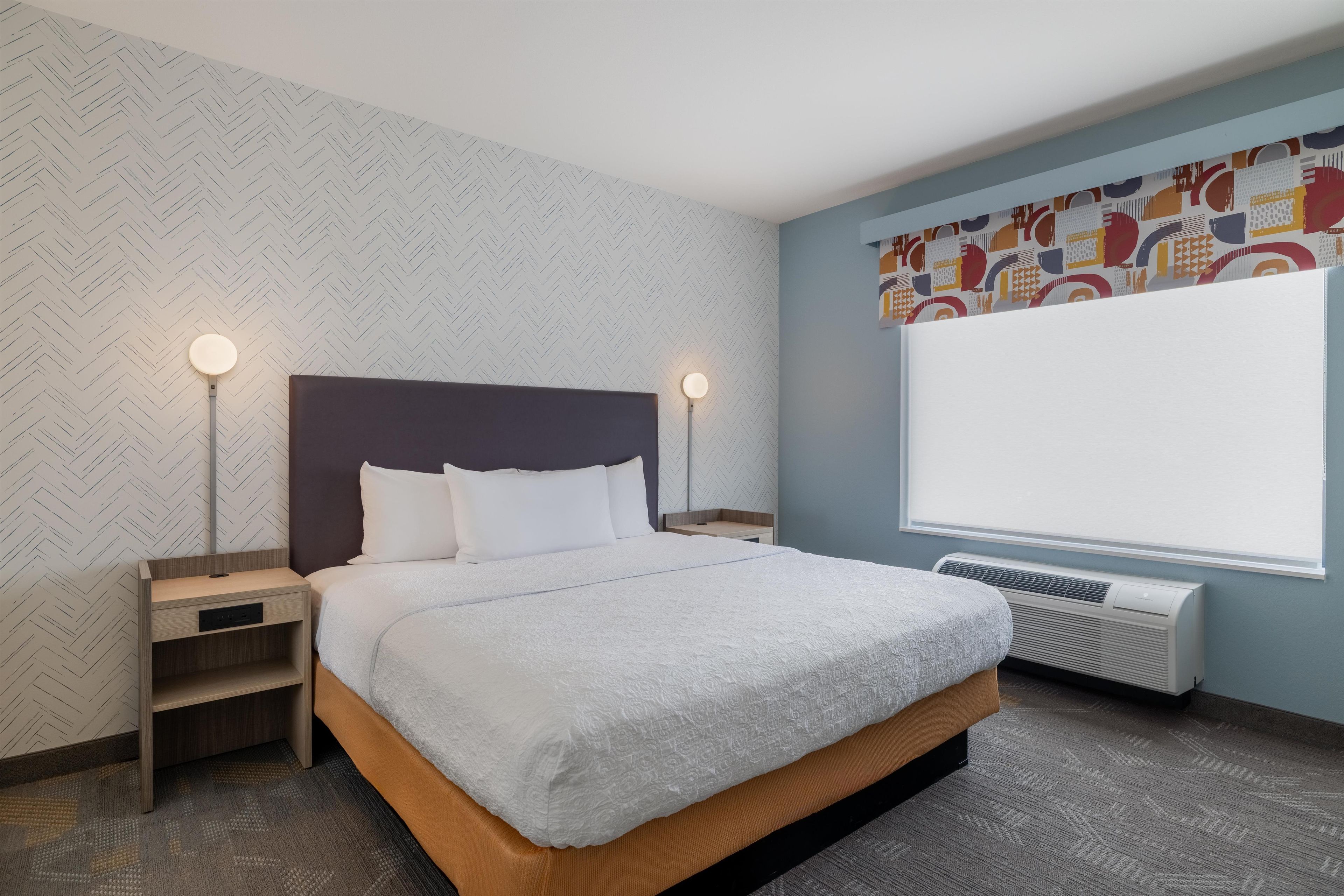 Ein Hotelzimmer mit Bett, Nachttischen, einem Heizkörper und einem Fenster mit Blick.