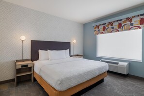 Een hotelkamer met een bed, nachtkastjes, een verwarming en een raam met uitzicht.