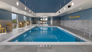 Ein Hallenbad mit klarem Wasser, blauer Decke und einem Schild an der Wand mit der Aufschrift 'Poolside is my vibe'.