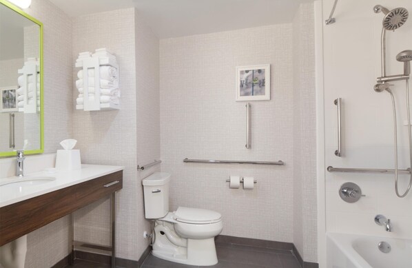 A modern bathroom with a white sink, toilet, and shower. There are towels and toiletries visible.
