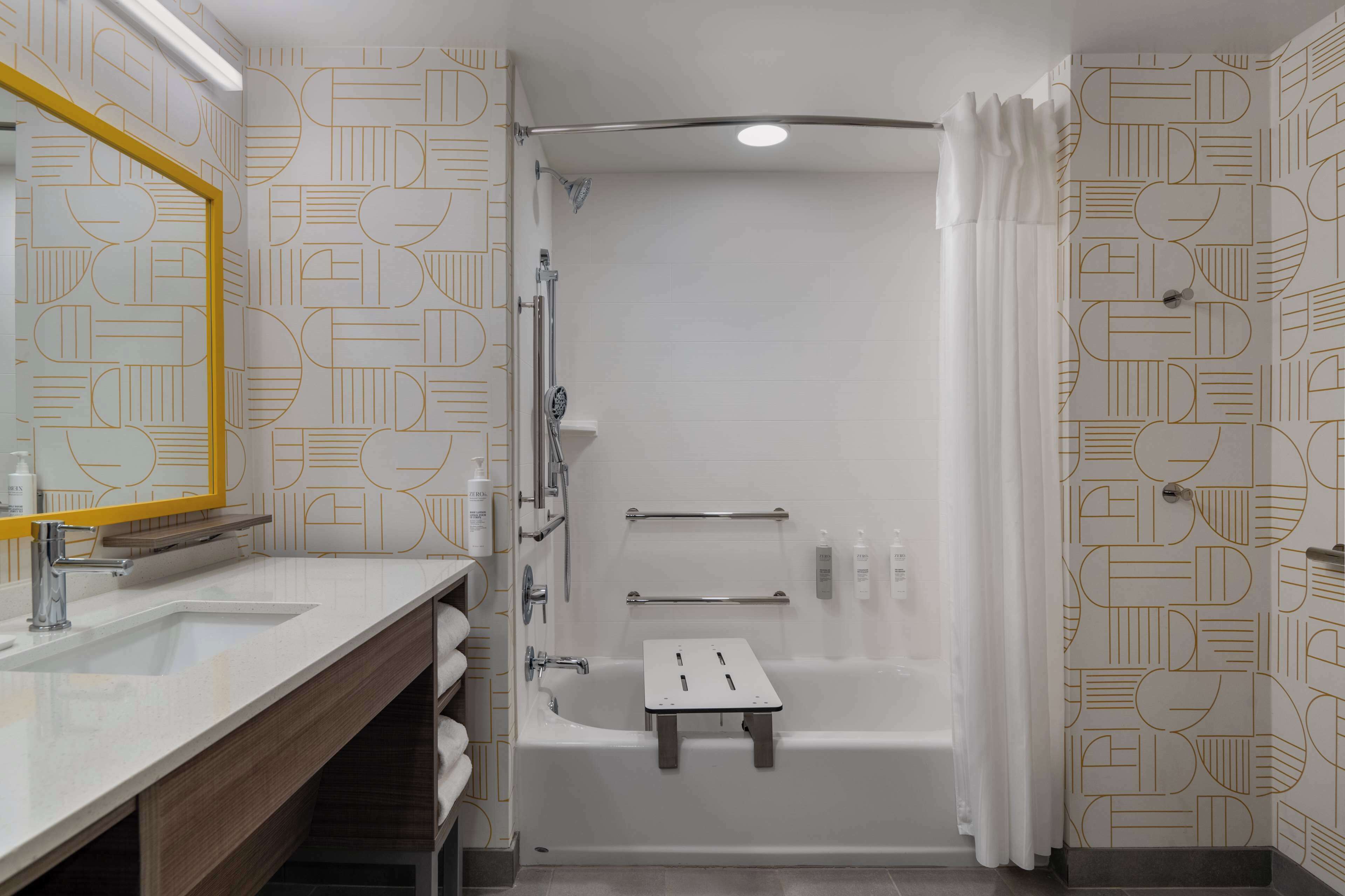 Een moderne badkamer met een douche, een wastafel met spiegel en een handdoekrek.