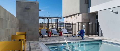 A rooftop pool area with a clear blue sky, a swimming pool, and lounge chairs.
