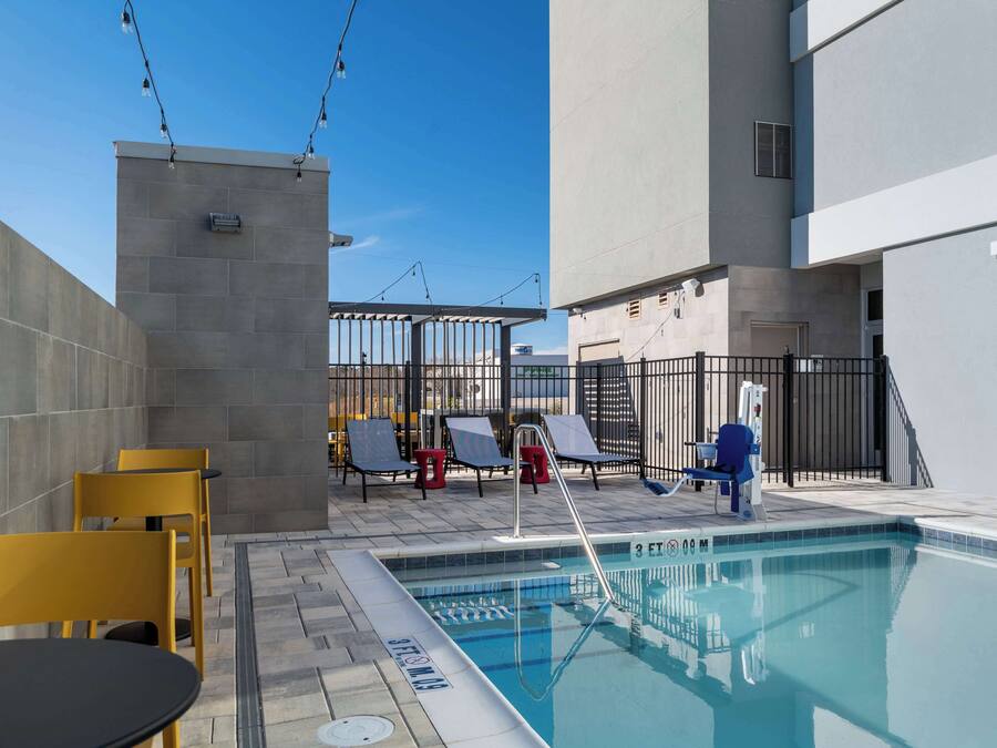 A rooftop pool area with a clear blue sky, a swimming pool, and lounge chairs.