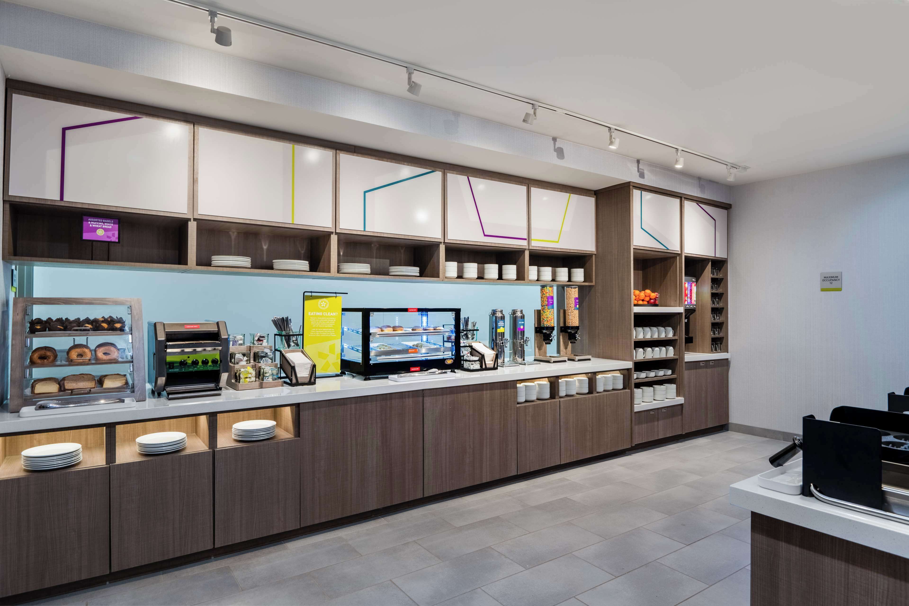 Una cafetería moderna con autoservicio, máquinas de café y una variedad de alimentos.
