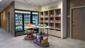 A snack kiosk with a variety of snacks and drinks, including chips and bottled water. - Home2 Suites By Hilton Troy, Al (Troy)