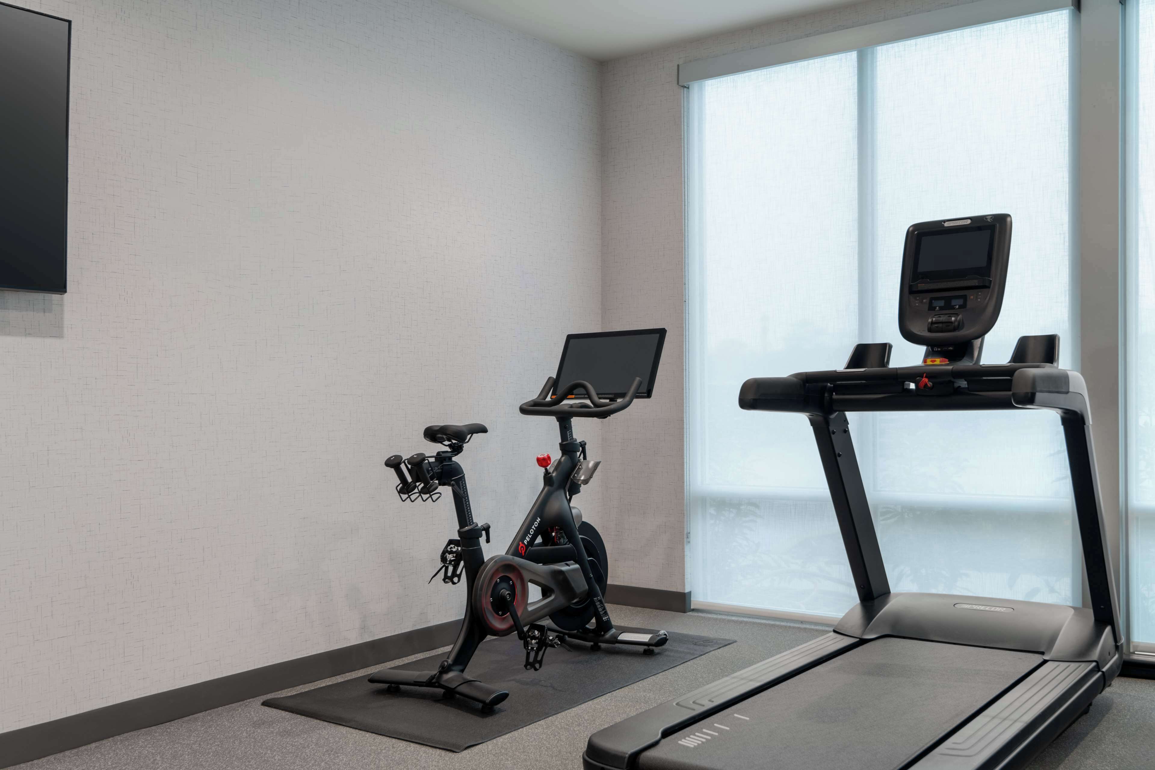 A gym with a stationary bike, a treadmill, and a large window.