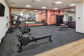Uma academia com máquinas de cardio, equipamentos de musculação e espelhos.