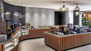 Una barra de desayuno moderna con diseño curvo, que ofrece diversos alimentos y una estación de café.