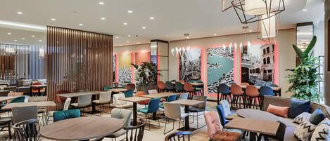 A modern restaurant with round tables and chairs, a wooden partition, and a large plant.