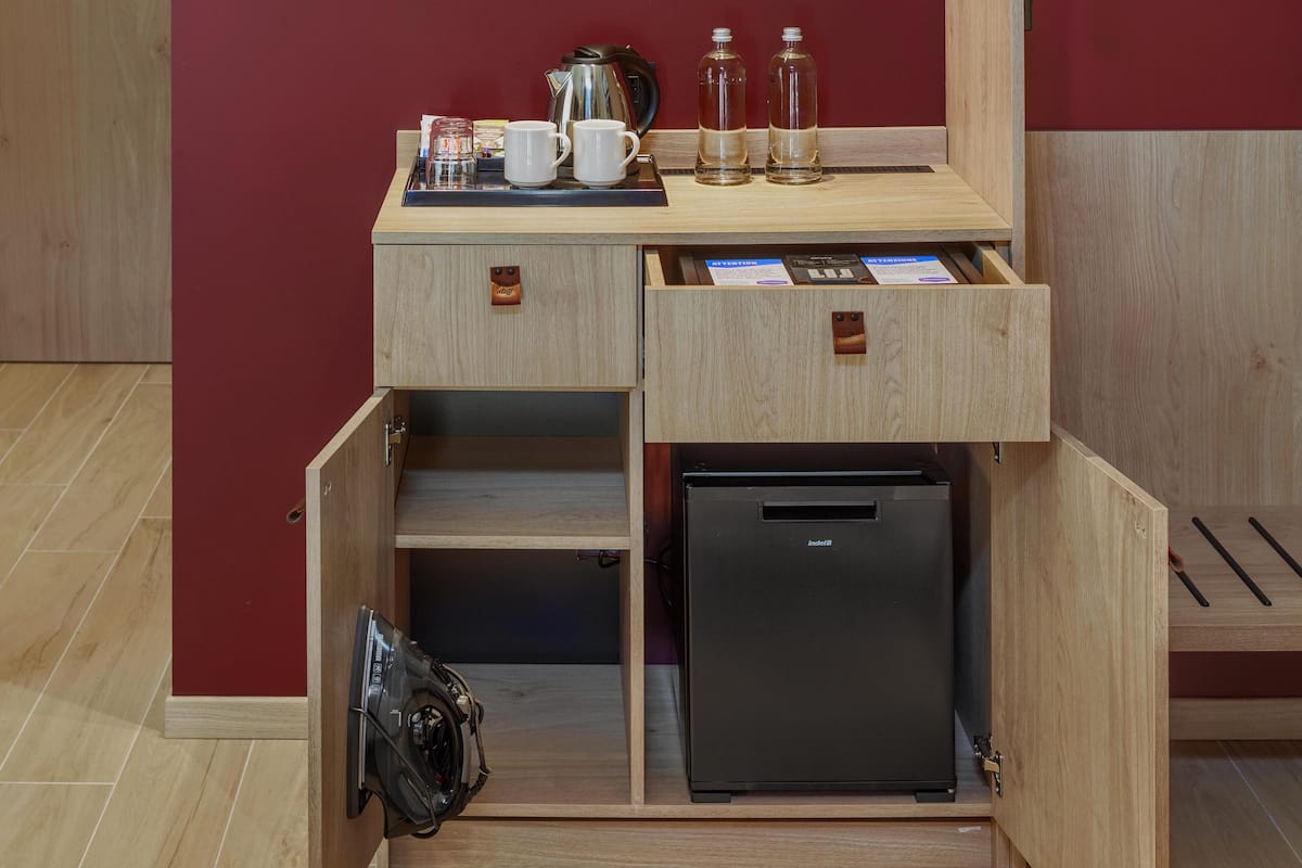 Una kitchenette compacta con refrigerador integrado, cafetera y tetera.