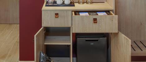 A compact kitchenette with a built-in refrigerator, a coffee maker, and a kettle.