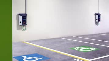 Un espace de stationnement comprenant des places réservées aux personnes handicapées et des bornes de recharge pour véhicules électriques.