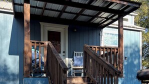 A blue cottage with a wooden porch and a sign reading "Blue Cottage."
