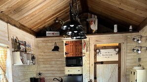 A rustic kitchen with wooden cabinets, a central island, and a farmhouse-style ceiling. - Tiny Farmhouse Pickleball Court and Pet Friendly! (Granbury)