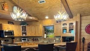 A kitchen with wooden cabinets, a stone island with bar stools, and pendant lighting. - Great family retreat! Pickleball  and pet friendly (Granbury)