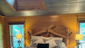 A wooden bed with a unique design, two bedside lamps, and a view of the outdoors through a skylight. - Great family retreat! Pickleball  and pet friendly (Granbury)